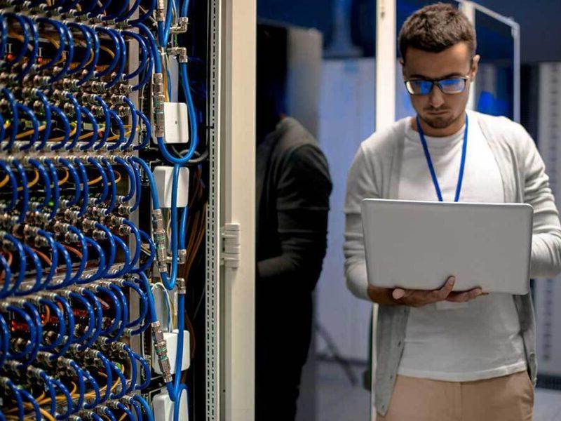 A man using a laptop in a server room with managed IT services in Boston.